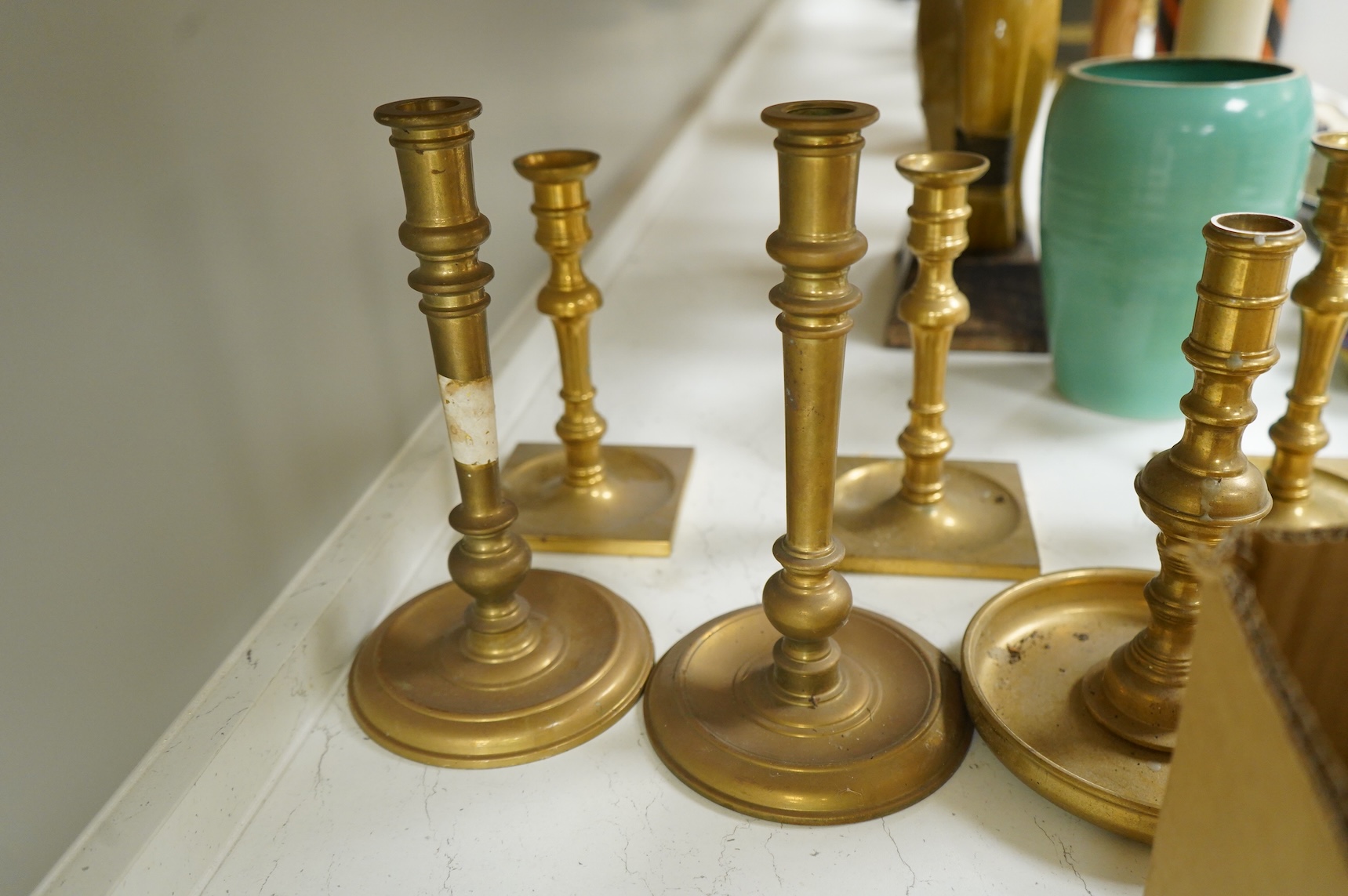 Two fire marks and a collection of brass candlesticks, tallest 25.5cm